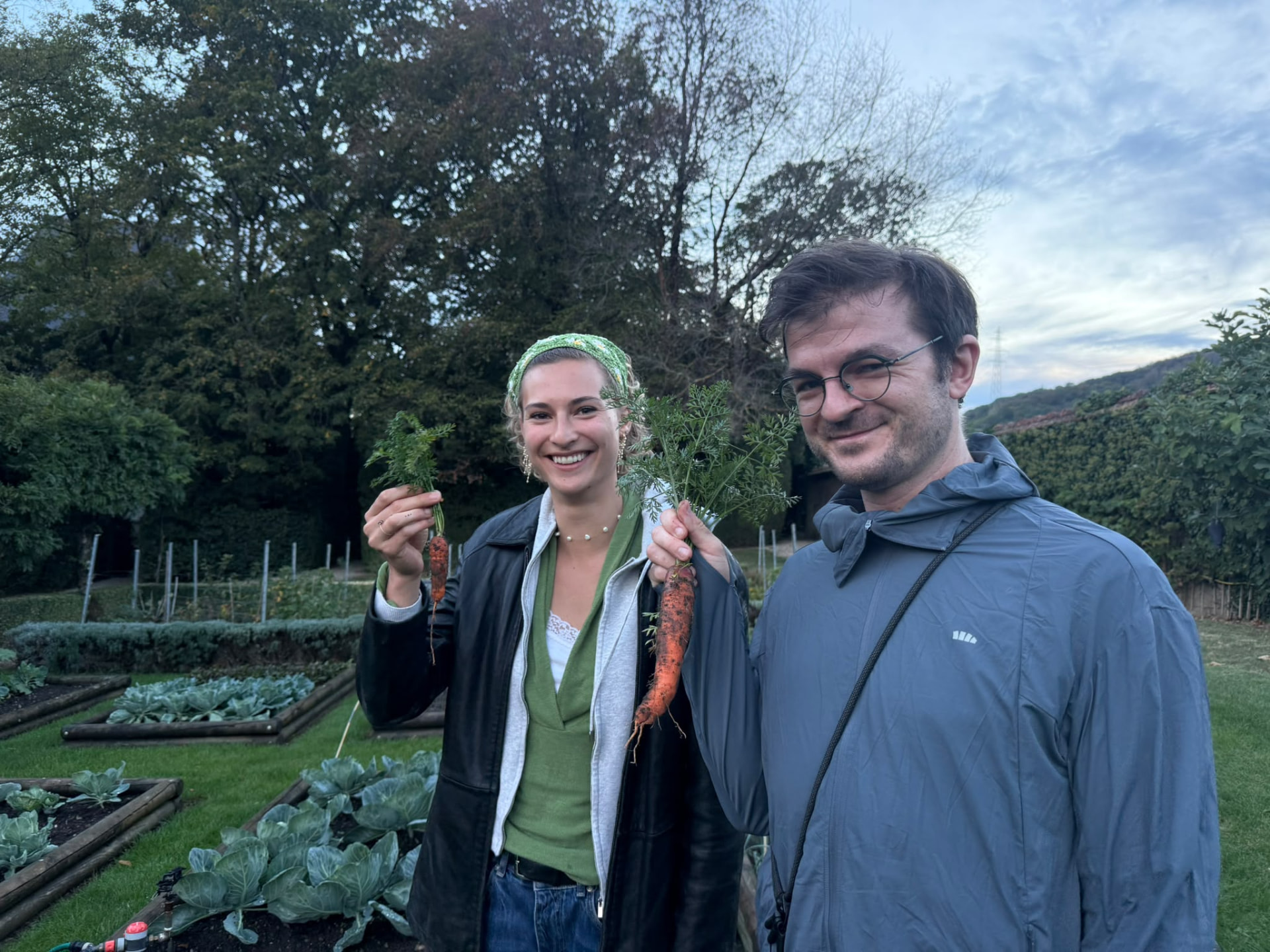 Members of the film team holding carrots in a vegetable garden